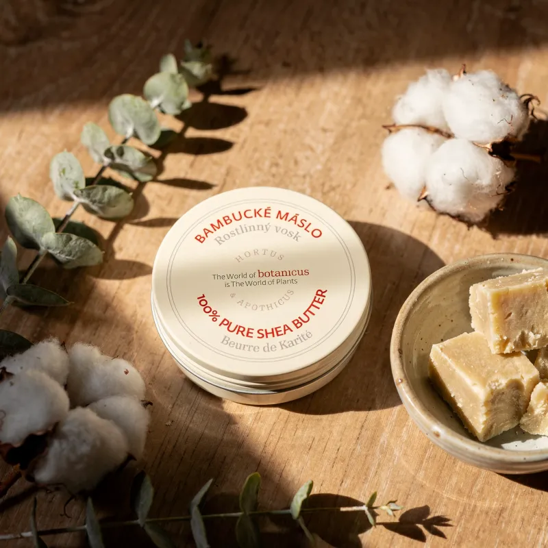 Cutie rotundă cu cremă de exfoliant/cremă de corp pe masă de lemn, alături de buchete de eucalipt și bumbac, cu bucăți de săpun/