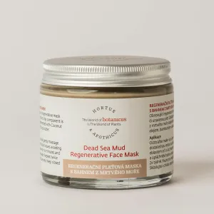 Unt de față într-un borcănel de sticlă cu capac metalic, etichetă albă/cre pe fond transparent, text „Dead Sea Mud Regenerative Face Mask” and detalii despre produse naturiste.